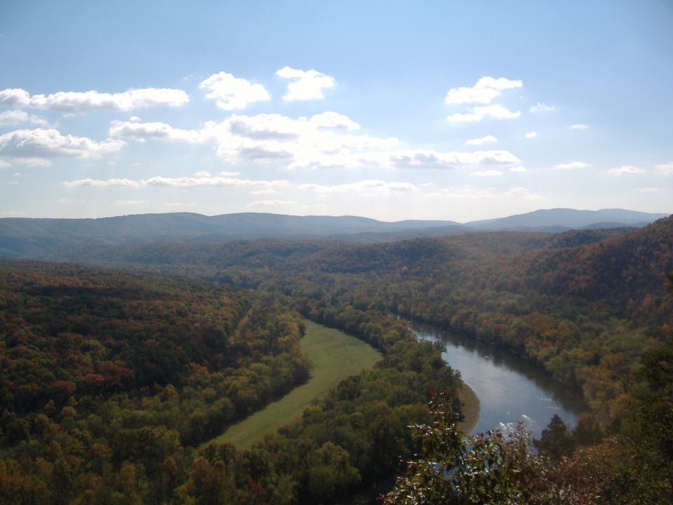 River valley with autumn foliage and a blue sky with clouds. Supermotors.net logo visible