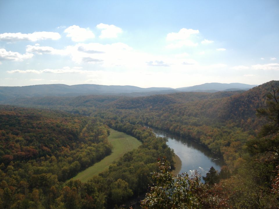 Scenic landscape with winding river and autumn trees under a blue sky with clouds