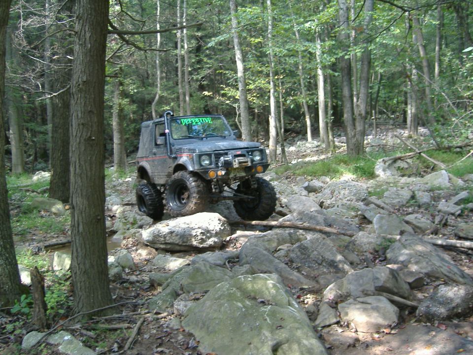 Black Suzuki Samurai with lifted suspension and large tires on a rocky trail