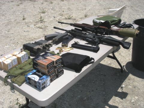 1990 Ford Bronco - Firearms and ammunition are laid out on a table outdoors.