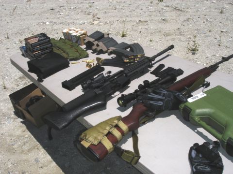 1990 Ford Bronco - Various firearms and ammunition are displayed on a table outdoors, ready for use.