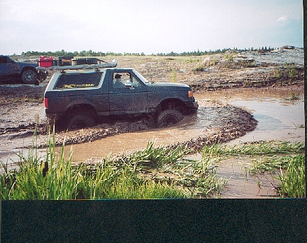 1989 Ford Bronco - This 1989 Ford Bronco is deep in a mud pit, with another vehicle in the background.