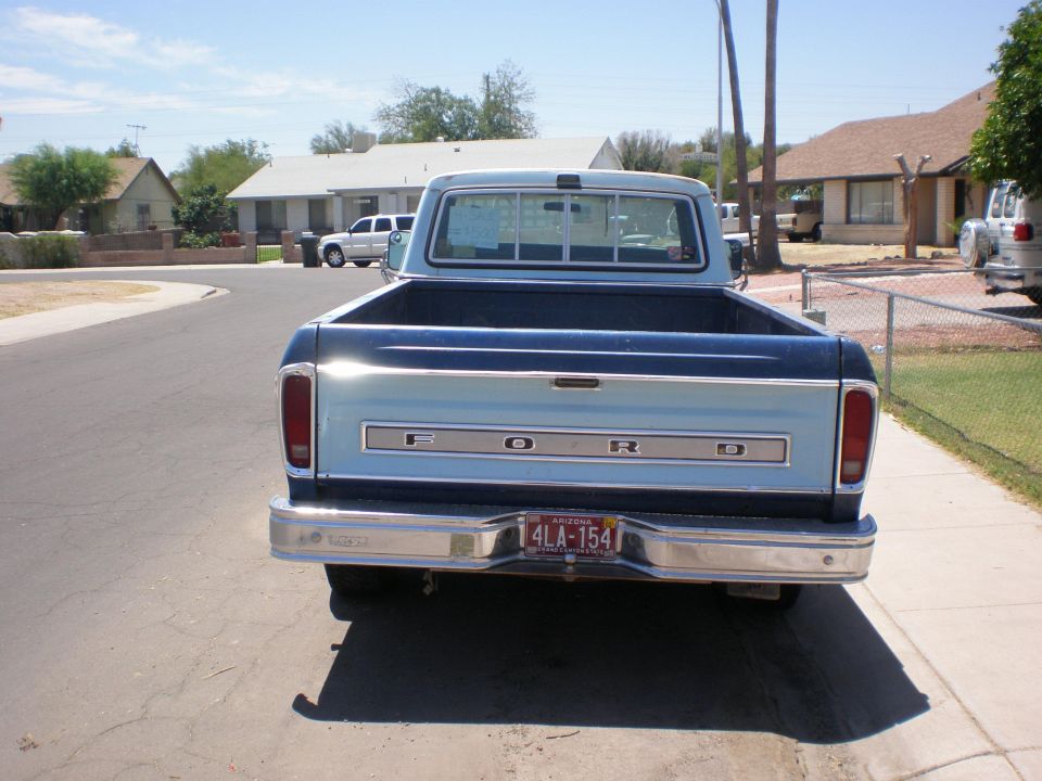 Rear view of a light blue Ford pickup truck with a dark blue stripe. License plate is visible