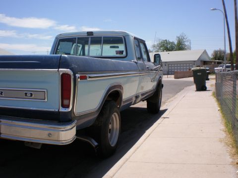 1978 Ford F-250 - A two-tone pickup truck is parked on a residential street next to a sidewalk and a trash can.