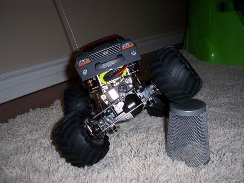 1996 Ford Bronco - A remote control monster truck is shown from the front, with its large tires and detailed chassis visible on a carpeted surface.