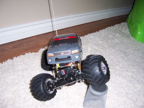 1996 Ford Bronco - A gray remote control monster truck with oversized tires is shown from the front on a carpeted floor.