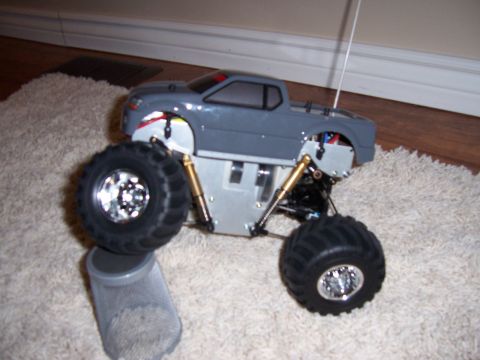 1996 Ford Bronco - A remote control monster truck is shown on a fluffy rug with its front wheel resting on a cylindrical object.