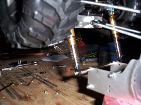1996 Ford Bronco - Close-up of RC car suspension components and tools scattered on a wooden workbench.