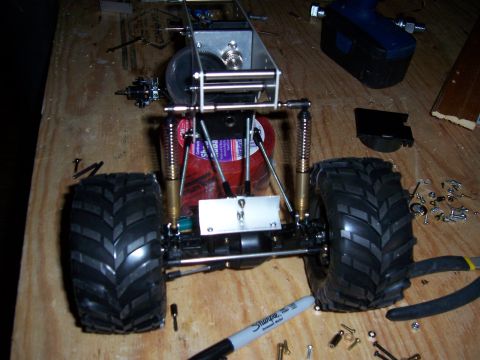 1996 Ford Bronco - A partially assembled remote control car chassis is shown on a workbench with various parts and tools scattered around.