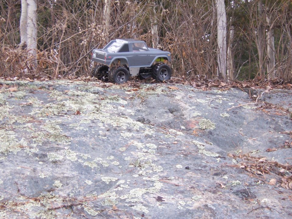 Gray remote control truck on rocky terrain with trees in background