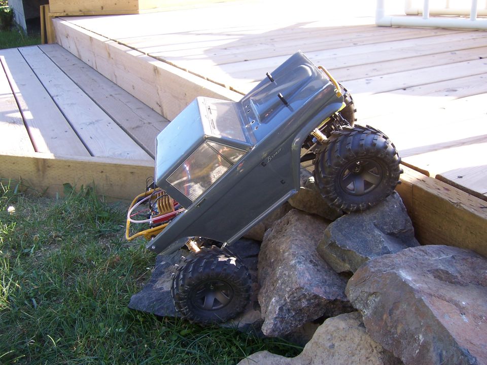 Gray RC rock crawler on rocks, side view