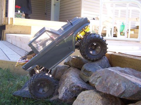 1996 Ford Bronco - RC rock crawler truck navigating a rocky obstacle course outdoors.