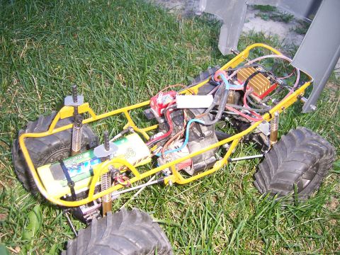1996 Ford Bronco - The internal components of a remote control buggy are visible, including the battery and wiring, resting on a grassy surface.