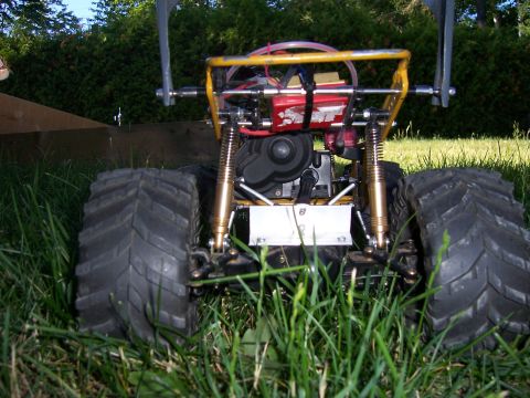 1996 Ford Bronco - Rear view of a remote control monster truck with exposed engine and large tires, set in grass.