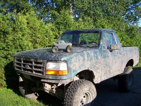 1996 Ford Bronco - A muddy 1996 Ford F-150 pickup truck sits outside with a small toy truck on its hood.