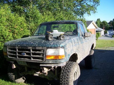 1996 Ford Bronco - A heavily muddied 1992 Ford F-150 pickup truck is shown from the front, with a small toy truck placed on its hood.