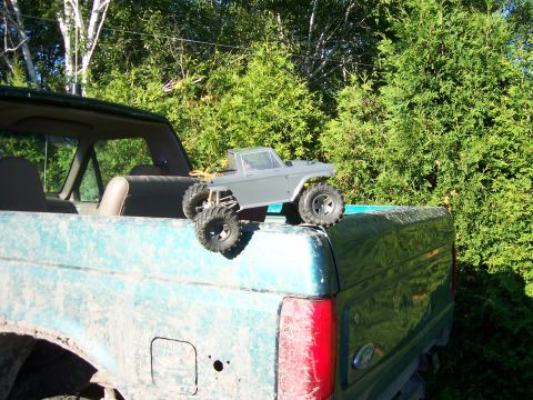 1996 Ford Bronco - RC truck placed on the bed of a teal pickup truck, with trees in the background.
