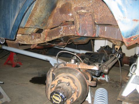1992 Ford Mustang - The underside of a vehicle is shown with significant rust on the frame and suspension components.