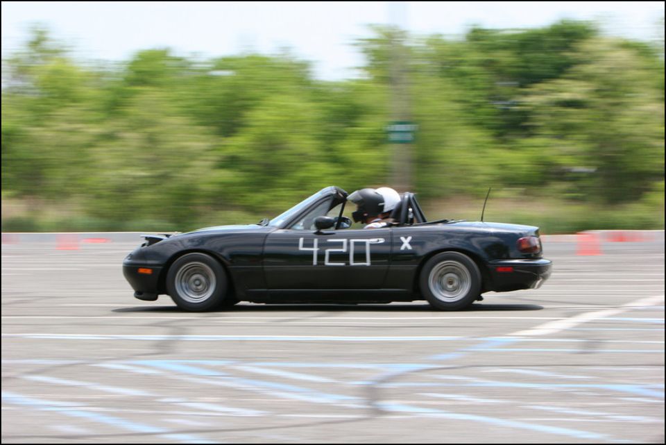 Black convertible with number 420 on the door, driver wearing helmet, on a track