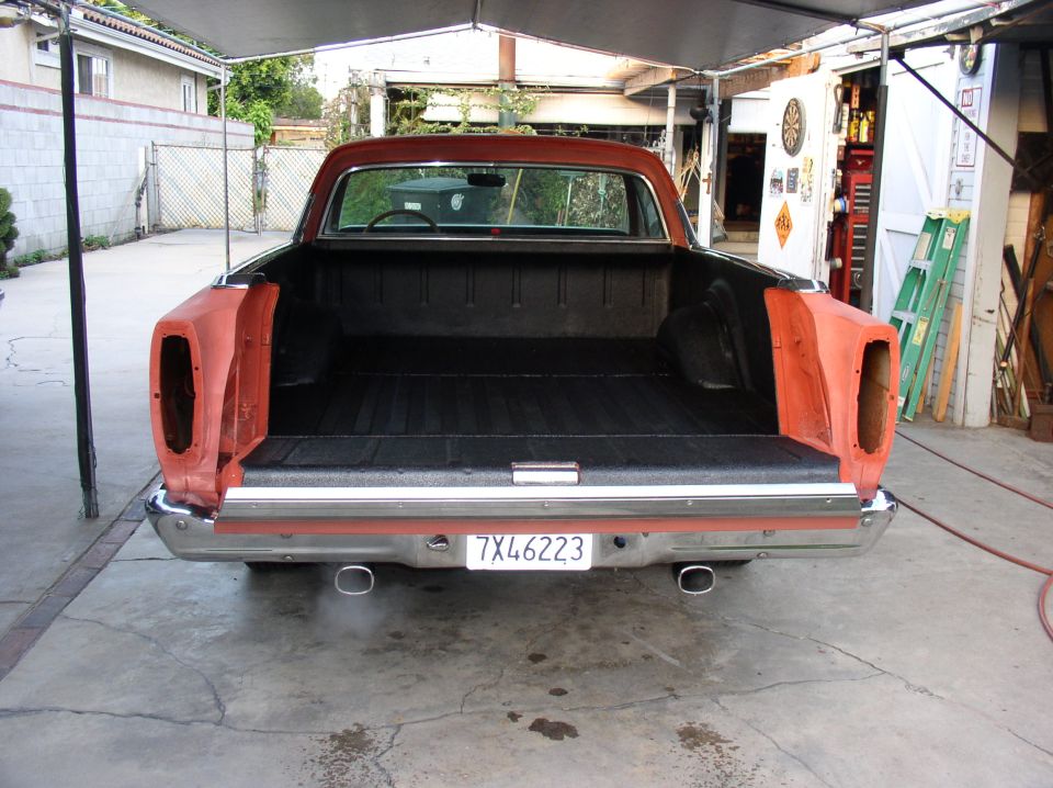 Rear view of orange Ford Ranchero with tailgate off, black bedliner, missing taillights, plate 7X46223
