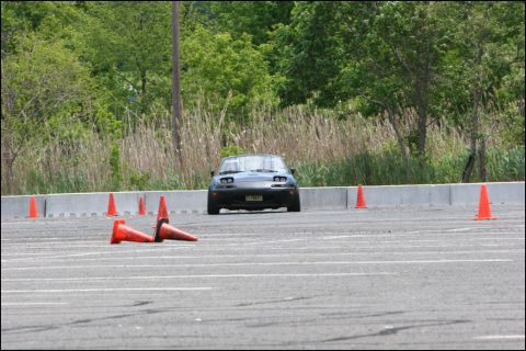 2001 Mercury Grand Marquis - A black Mazda Miata is positioned on a paved surface marked with white lines and surrounded by orange traffic cones.