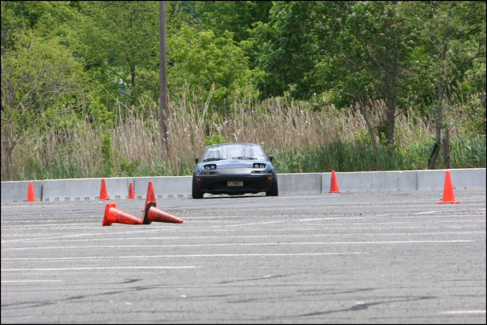 Black Mazda Miata on a track with orange cones