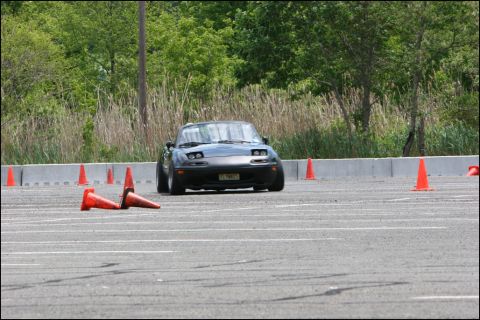 2001 Mercury Grand Marquis - A dark gray Mazda Miata navigates an autocross course marked by orange cones.