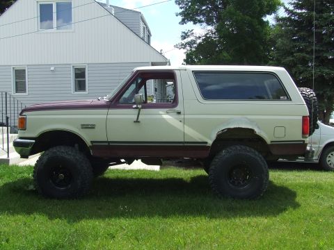 1990 Ford Bronco - This lifted Ford Bronco features a two-tone paint scheme and is equipped with large off-road tires for enhanced capability.