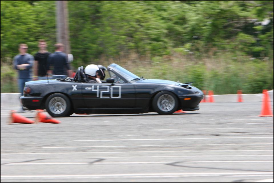 Black convertible sports car with racing numbers "X -420" on the side, seen from the side at an autocross event