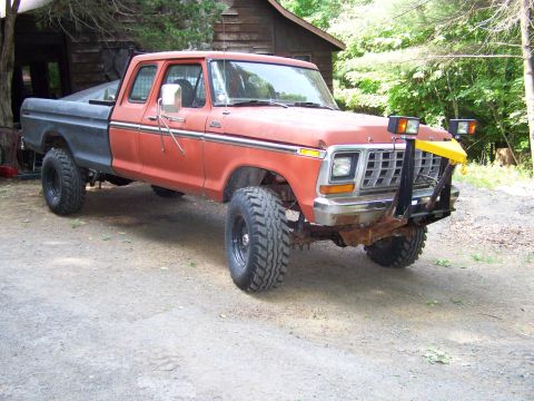 1979 Ford Bronco - This modified Ford F-Series truck, likely from the late 1970s, sits parked in a wooded area.