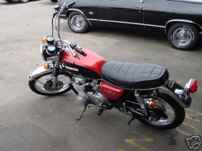1985 Ford Crown Victoria LTD - A red and black Honda motorcycle is parked next to a black car, with the motorcycle being the primary focus.