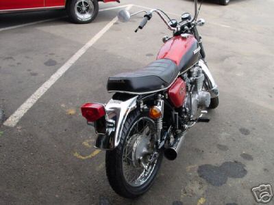 1985 Ford Crown Victoria LTD - A red and black motorcycle is parked in a lot, viewed from the rear. Chrome accents are visible on the fenders and wheels.