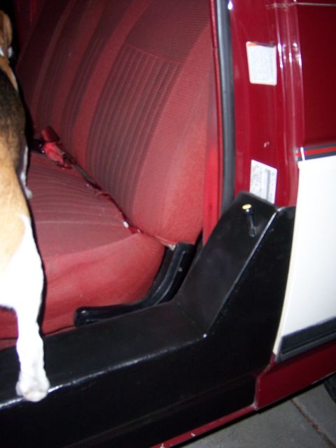 1991 Ford Bronco - A dog's paws rest on the interior trim of a vehicle, with a view of the red striped seats.