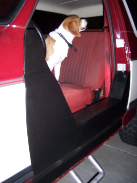 1991 Ford Bronco - A beagle sits in the red interior of a vehicle, looking out the open door.