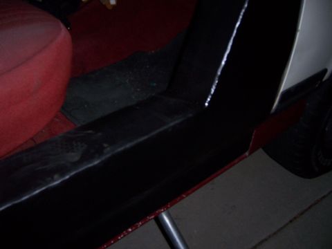1991 Ford Bronco - Close-up view of a vehicle's interior, highlighting the red seat and black trim against a white exterior panel.