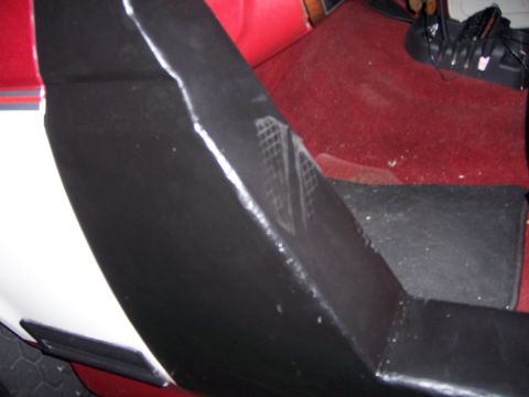 1991 Ford Bronco - Close-up view of the interior door panel and red carpet, with a black shoe visible in the upper right corner.