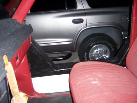 1991 Ford Bronco - A silver SUV is parked next to the interior of another vehicle, showing a side view of the SUV's rear wheel.
