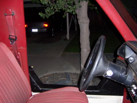 1991 Ford Bronco - Interior view of a 1991 Ford Bronco, showing red seats and steering wheel, with another vehicle visible outside.