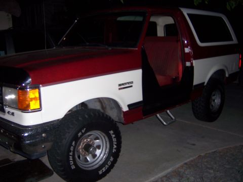 1991 Ford Bronco - This two-tone Ford Bronco features an open driver's door and a '4x4' badge on the front fender.