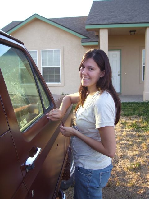 1990 Ford Bronco - A woman poses next to a brown SUV in front of a house.