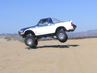 1996 Ford Bronco - This 1996 Ford Bronco is captured mid-air during an off-road excursion on a sandy terrain.