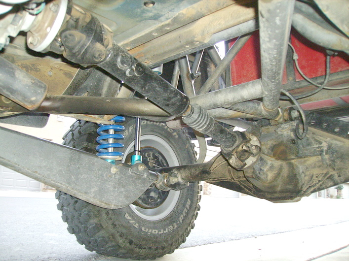Undercarriage of a modified off-road vehicle showing suspension, driveshaft, and differential