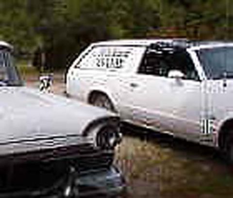 1971 Ford Ranchero - A white pickup truck with racing decals is parked outdoors, with another vehicle partially visible.