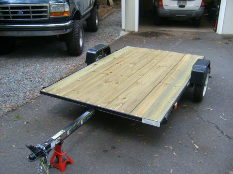 1994 Ford Bronco - A dark green 1992-1997 Ford F-250/F-350 is parked next to a wooden utility trailer.