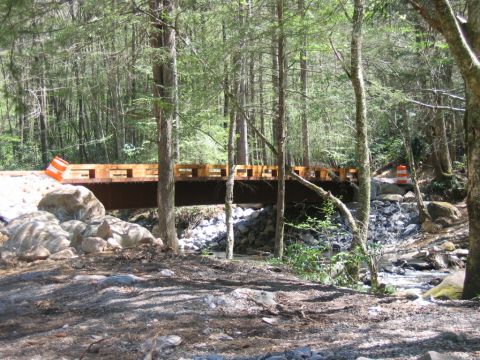1992 Ford Mustang - A bridge is being constructed over a rocky stream in a wooded area.
