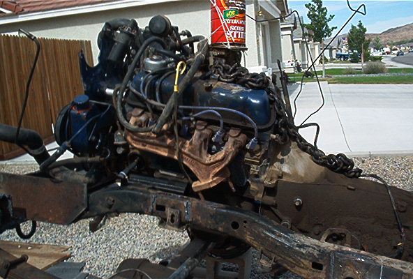 V8 engine on a stand, looks like a Ford 351 Windsor. Can see a can of oil on top