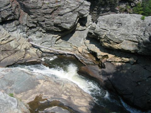 1985 Ford LTD Crown Victoria - A natural scene of a stream flowing through a rocky gorge, with a fallen log across the water.