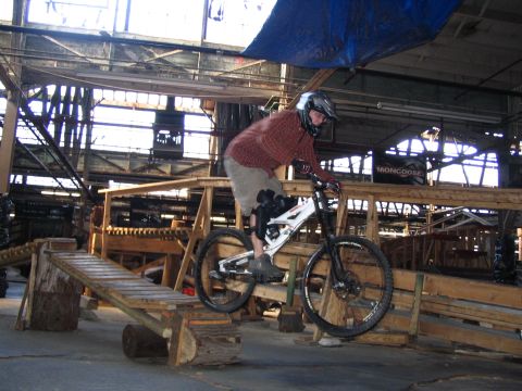 1997 Ford Probe - A person rides a mountain bike on a wooden obstacle course inside a warehouse.