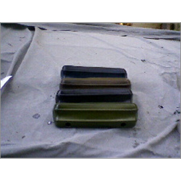 stack of car bumpers, some green, some black, one brown, one dark blue