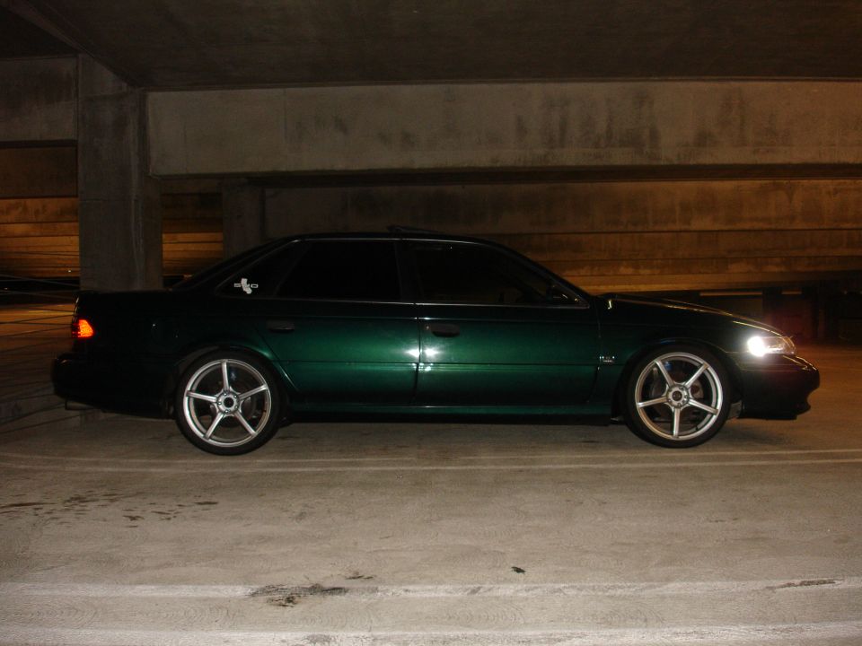 Dark green Ford Taurus SHO sedan at night in parking garage on five-spoke wheels